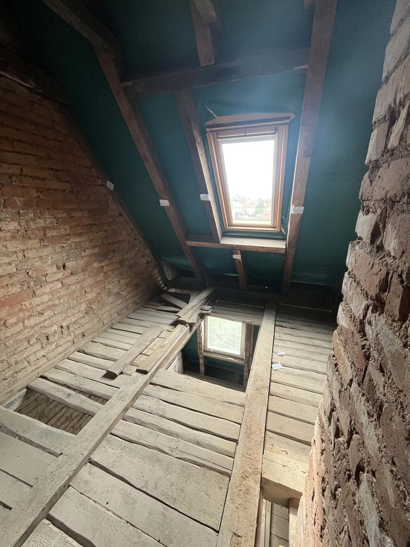 Dachgeschoss im Rohbau mit offenen Sparren und eingebautem Dachfenster