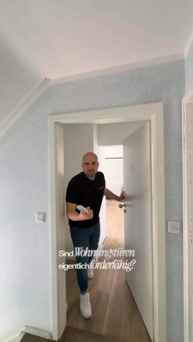 Standbild aus einem Beitrag: Ein Mitarbeiter öffnet eine Wohnungstür in einem hellen Flur, dazu die Frage „Sind Wohnungstüren eigentlich förderfähig?“.